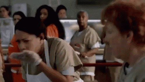 a group of women in orange jumpsuits are standing in a prison cell .