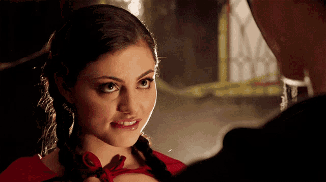 a woman in a red dress looks at a man in a black shirt