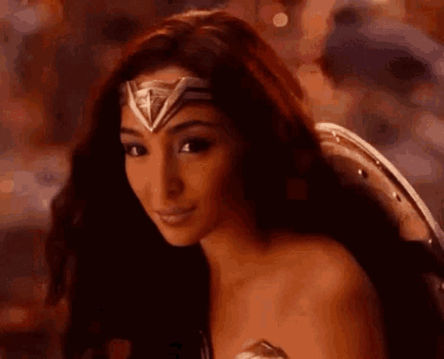 a woman in a wonder woman costume is smiling and wearing a headband .
