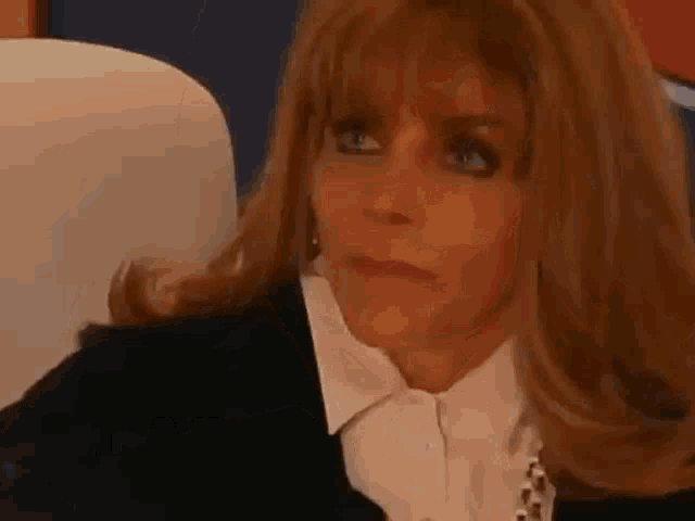 a woman in a black jacket and white shirt is sitting in a chair .