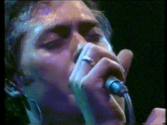 a close up of a man singing into a microphone with a ring on his finger