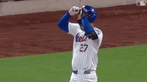 a mets baseball player wearing number 27 holds his helmet