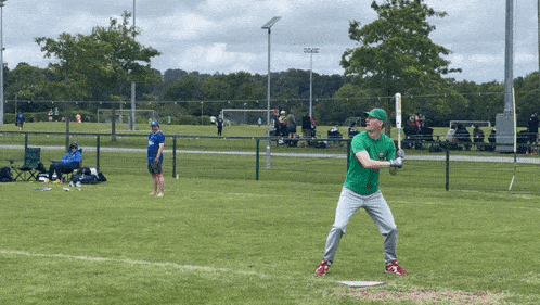 a man in a green shirt is swinging a baseball bat