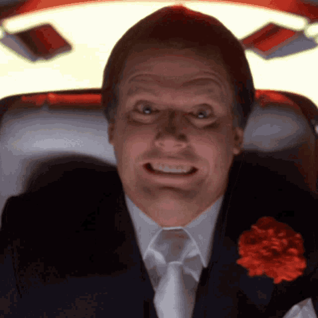 a man in a suit and tie with a red flower in his pocket is smiling