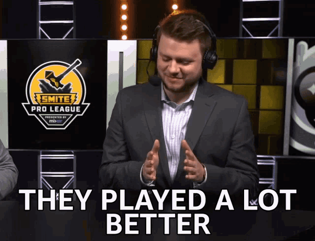 a man wearing headphones says they played a lot better in front of a smite pro league logo
