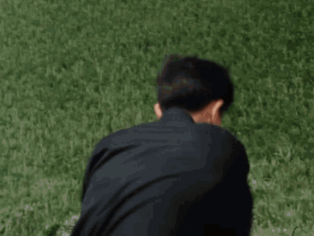 a young boy is throwing a frisbee in the air while standing in the grass .