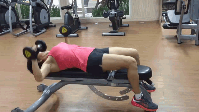 a woman is laying on a bench lifting a dumbbell