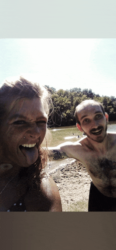 a man and a woman are posing for a picture on the beach and the woman is sticking her tongue out