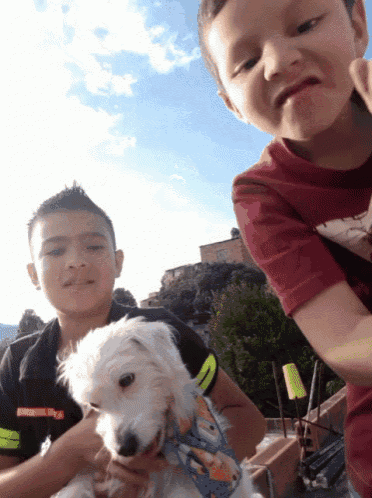 two young boys are holding a small white dog and one boy is wearing a red shirt that says ' nike ' on it