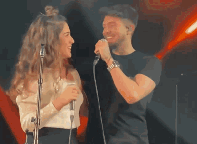 a man and a woman are singing into microphones on stage