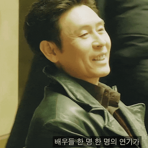 a man in a leather jacket is smiling with a sticker that says ' a ' on it