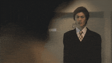a man in a suit and tie is standing in front of a door that says ' no smoking ' on it
