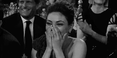 a woman is laughing while sitting in a crowd of people .