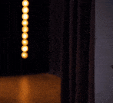 a row of lights are hanging from a curtain in a dark room .