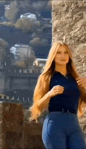 a woman with long red hair is standing in front of a stone wall .