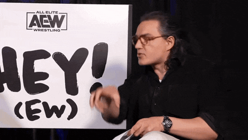 a man is standing in front of a sign that says aew wrestling