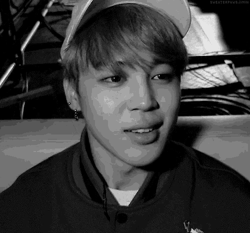 a black and white photo of a young man wearing a baseball cap and smiling .