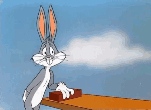 bugs bunny is sitting at a table pressing a button .