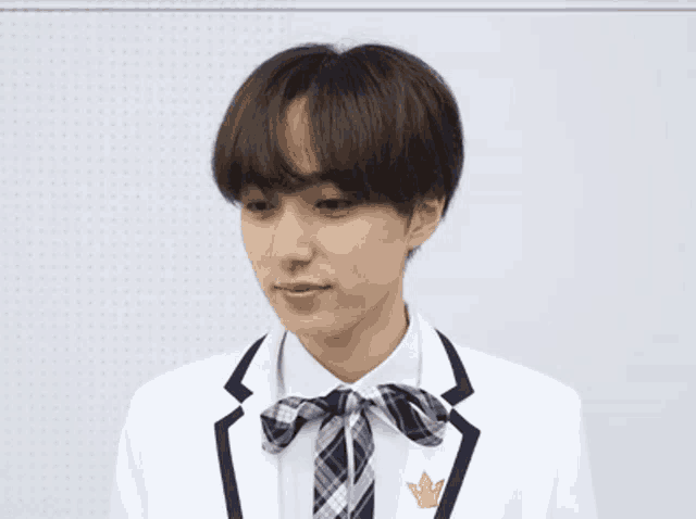 a young man wearing a white suit with a plaid bow tie