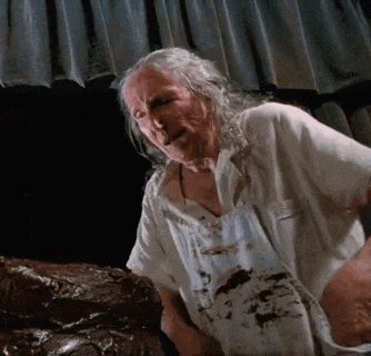 an elderly woman is sitting on a couch with a piece of meat in her hand .