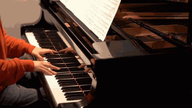 a person playing a piano with a sheet of music on top of it
