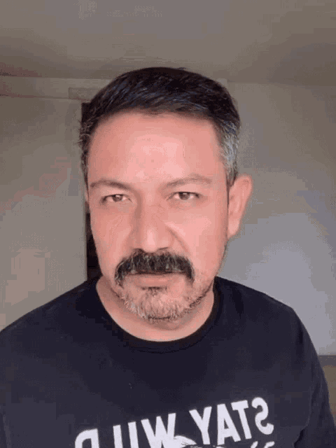 a man with a mustache is wearing a black shirt that says ' always ' on it