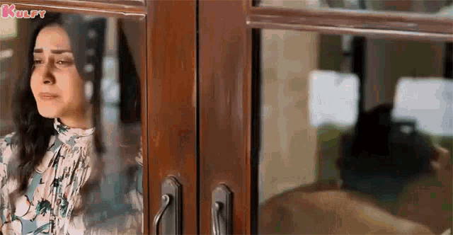 a woman is standing in front of a glass door with the word kulfy on the bottom