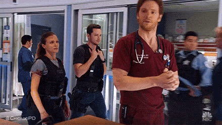 a man with a stethoscope around his neck is standing next to a woman in a hospital .