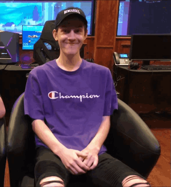 a man wearing a purple champion shirt smiles for the camera