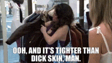 a woman is holding a jacket in a store with a caption that says ooh and it 's tighter than dick skin man