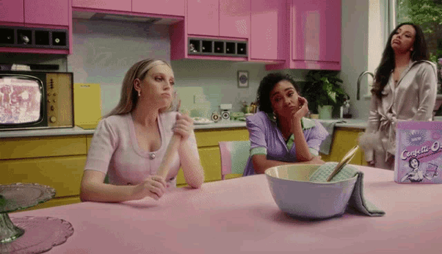 three women are sitting at a table with a box of crispette oats on it
