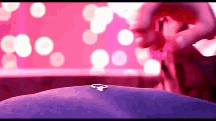 a close up of a person holding a ring on a purple surface .