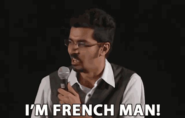 a man with glasses is holding a microphone and saying i 'm french man .