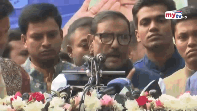 a man is giving a speech in front of a microphone with the words mytv on the bottom
