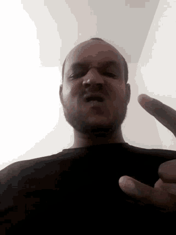 a man in a black shirt is giving a middle finger