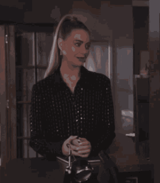 a woman in a sequined shirt is standing in front of a door