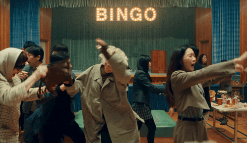 a group of people are dancing under a bingo sign