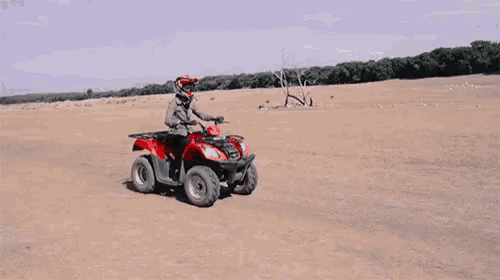 a person is riding a red atv in the desert .