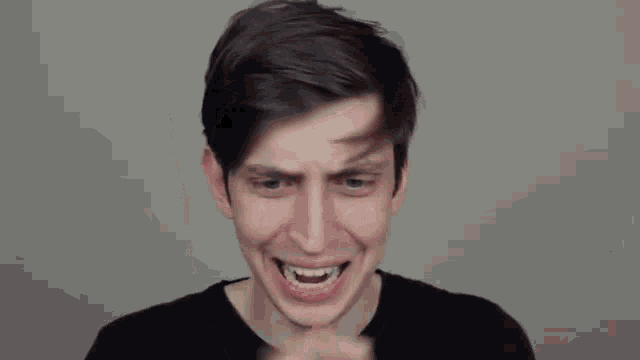 a young man is making a funny face with his hands to his face .