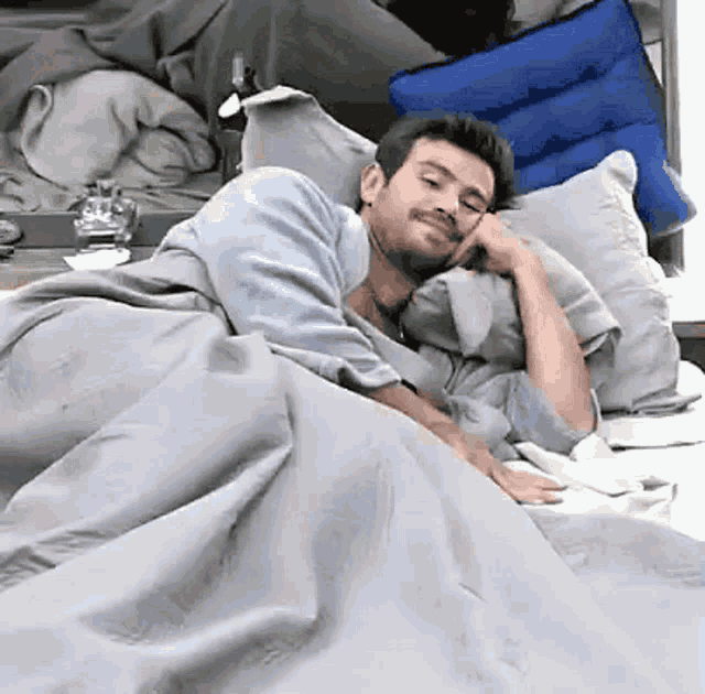 a man is laying in a bed with a gray blanket