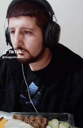 a man wearing headphones is looking at a plate of food with a tiktok logo above his head