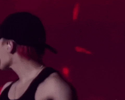 a man is sticking his tongue out while wearing a black tank top and a hat .