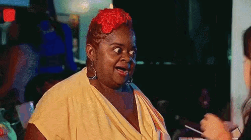 a woman with red hair is making a funny face while standing in front of a crowd .