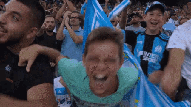 a crowd of people are watching a soccer game and one of them is wearing a shirt that says inter sport .