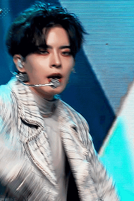 a close up of a man wearing a white jacket and a microphone in his mouth