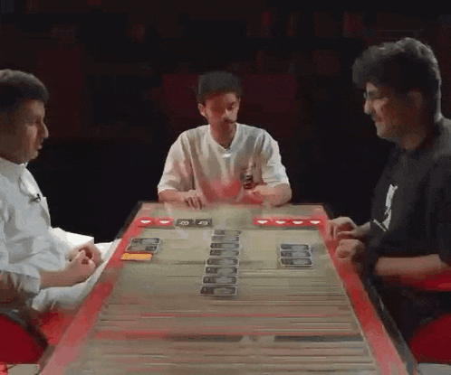 a group of men are playing a game of cards at a table .