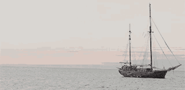 a sailboat is in the middle of the ocean at sunset