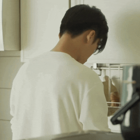 a man in a white shirt stands in a kitchen
