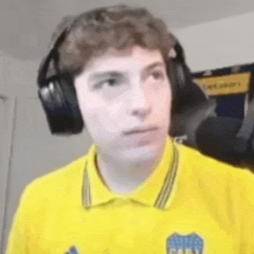 a young man wearing headphones and a yellow shirt is making a face .