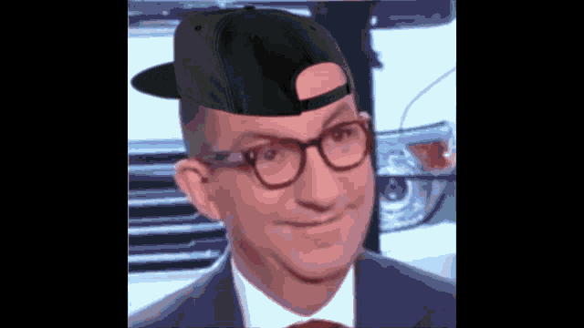 a man with glasses and a hat on his head looks at the camera